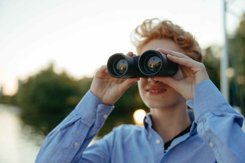 A young person uses binoculars during a nature observation adventure.